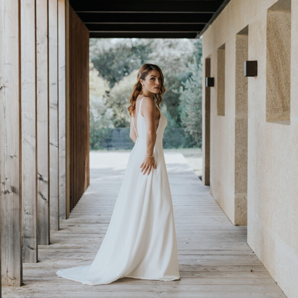 Mariée vue de profil, avec les cheveux détachés, portant des bijoux de mariage en forme de barette perlées dans sa coiffure.