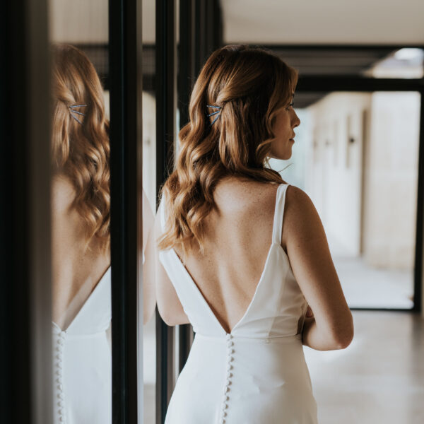 Mariée vue de dos, avec les cheveux détachés, portant des bijoux de mariage en forme de barette dans sa coiffure.