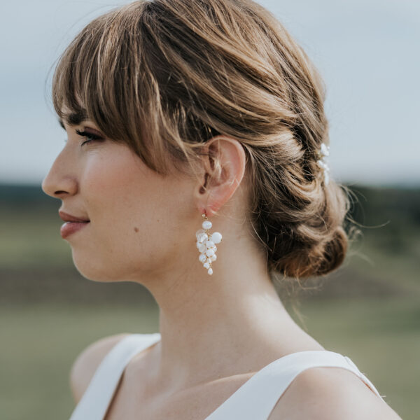 jeune mariée portant une paire de boucles d'oreilles de mariage faite d'une grappe de perles d'eau douce et de perles de porcelaine.