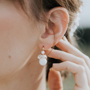 jeune mariée portant une paire de boucles d'oreilles de mariage faite d'une grappe de perles d'eau douce et de perles de porcelaine.