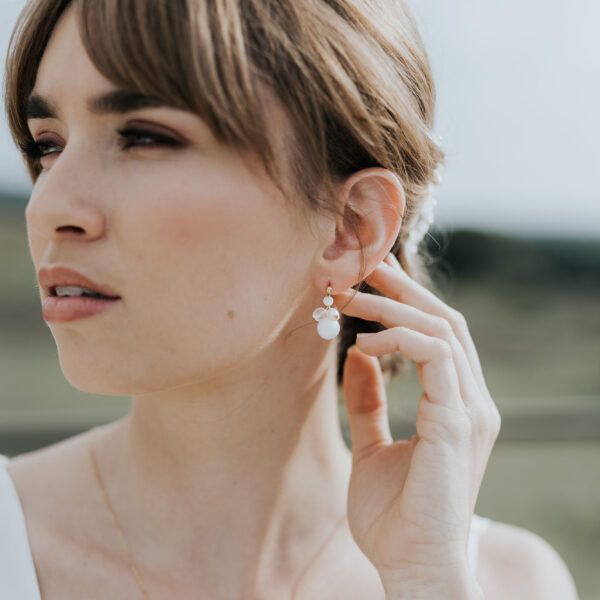 jeune mariée portant une paire de boucles d'oreilles de mariage faite d'une grappe de perles d'eau douce et de perles de porcelaine.