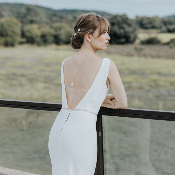 bijoux de mariage portés par une mariée vue de dos dans un paysage provençale. Elle porte un collier de dos en perles d'eau douce et en porcelaine ainsi que que de fines épingles à cheveux en perle et porcelaine.