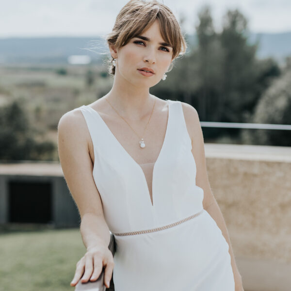 jeune mariée portant ses bijoux de mariage en perles d'eau douce et en porcelaine. Elle porte un collier pendant et des boucles d'oreilles.