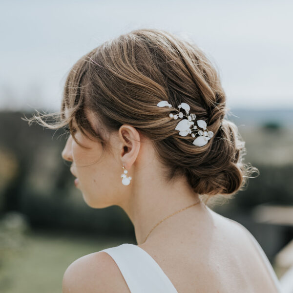 Coiffure de mariée habillée d'épingles à cheveux. Ces bijoux de mariage sont en perles d'eau douce et en porcelaine.