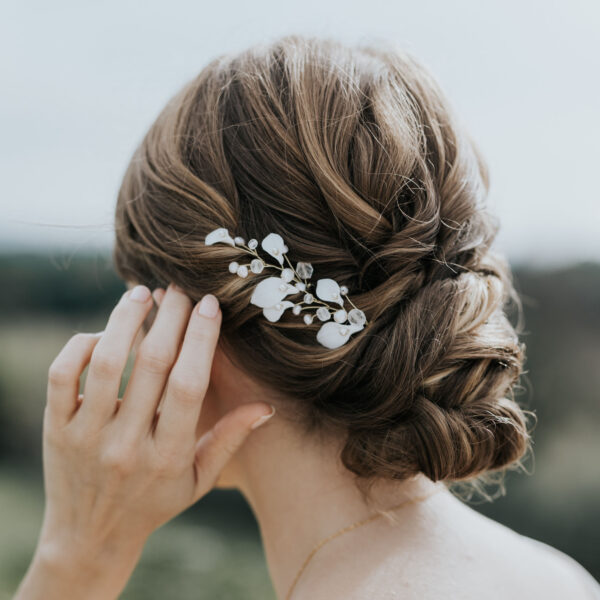 Coiffure de mariée habillée d'épingles à cheveux. Ces bijoux de mariage sont en perles d'eau douce et en porcelaine.