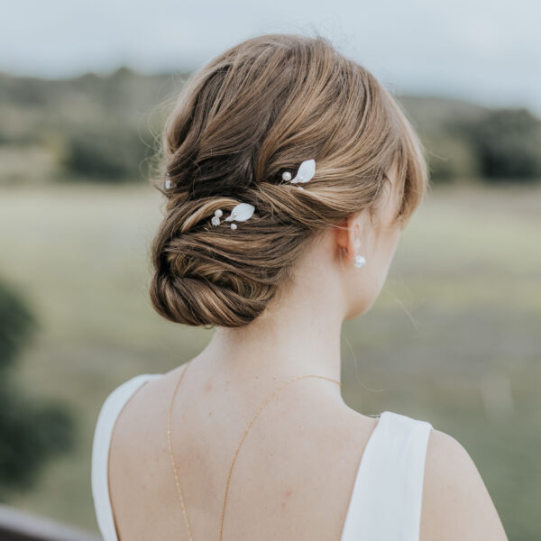 Coiffure de mariée habillée d'épingles à cheveux. Ces bijoux de mariage sont en perles d'eau douce et en porcelaine.