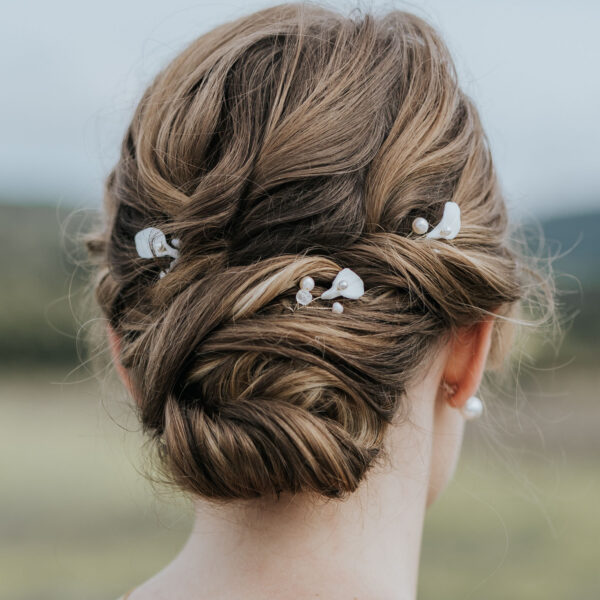 Coiffure de mariée habillée d'épingles à cheveux. Ces bijoux de mariage sont en perles d'eau douce et en porcelaine.