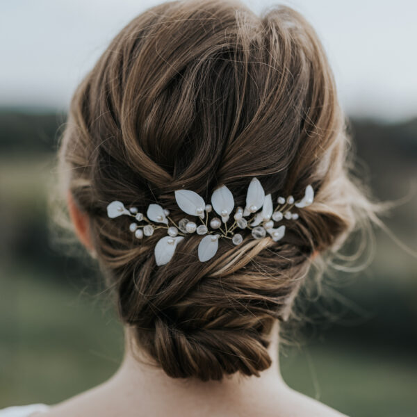 Coiffure de mariée habillée d'épingles à cheveux. Ces bijoux de mariage sont en perles d'eau douce et en porcelaine.