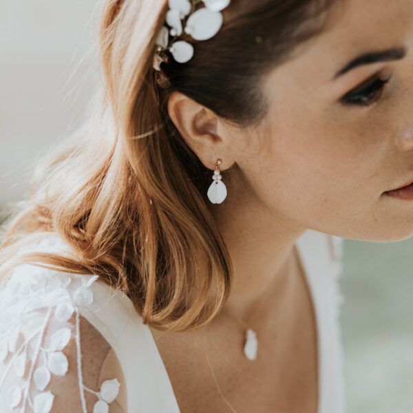 bijoux de mariage en porcelaine portés par une mariée. Elle porte une vigne de cheveux, des fines boucles d'oreilles et un collier pendant.