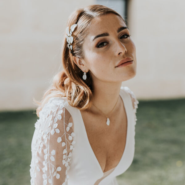 bijoux de mariage en porcelaine portés par une mariée. Elle porte une vigne de cheveux, des fines boucles d'oreilles et un collier pendant.