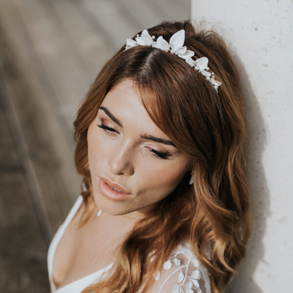 bijoux de mariage portés par une mariée. Elle porte un fin collier pendant avec une feuille en porcelaine, des boucles d'oreilles avec un pétale de poreclaine et une couronne de feuilles en porcelaine et perles de Swarovski.