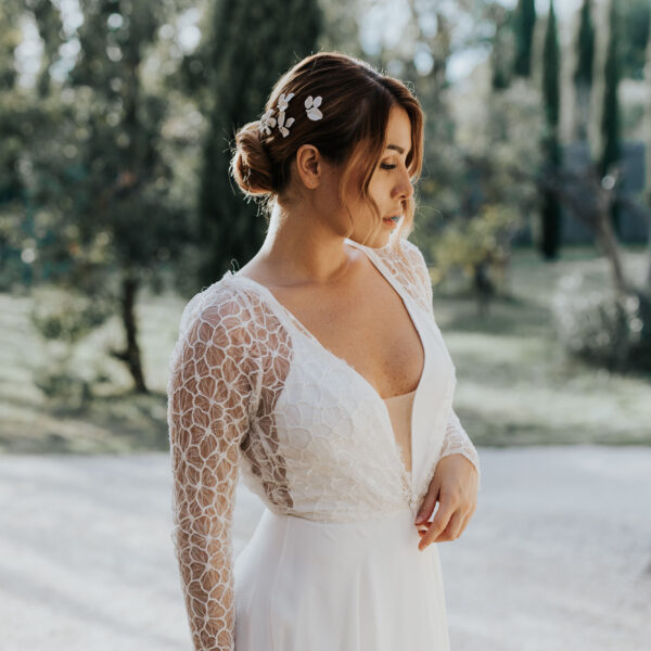 Coiffure de mariée élégante habillée d'épingles à chignon de mariage en porcelaine et perles de Swarovski.