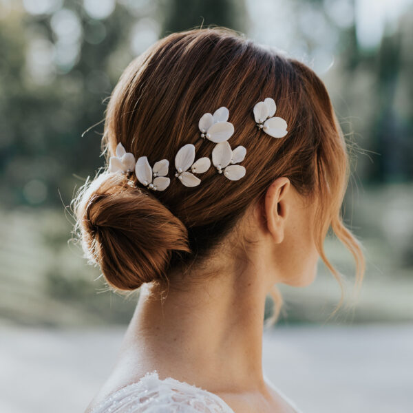 Coiffure de mariée élégante habillée d'épingles à chignon de mariage en porcelaine et perles de Swarovski.