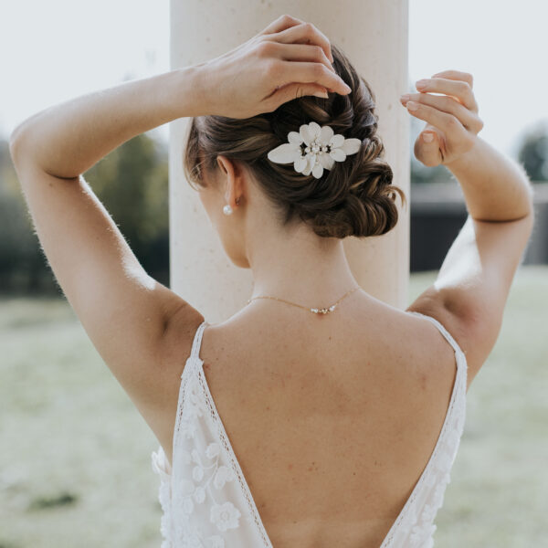 Coiffure de mariée élégante habillée d'un accessoire cheveux de mariage en porcelaine et perles de Swarovski.