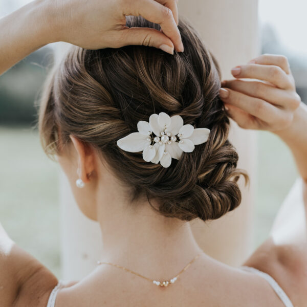 Coiffure de mariée élégante habillée d'un accessoire cheveux de mariage en porcelaine et perles de Swarovski.