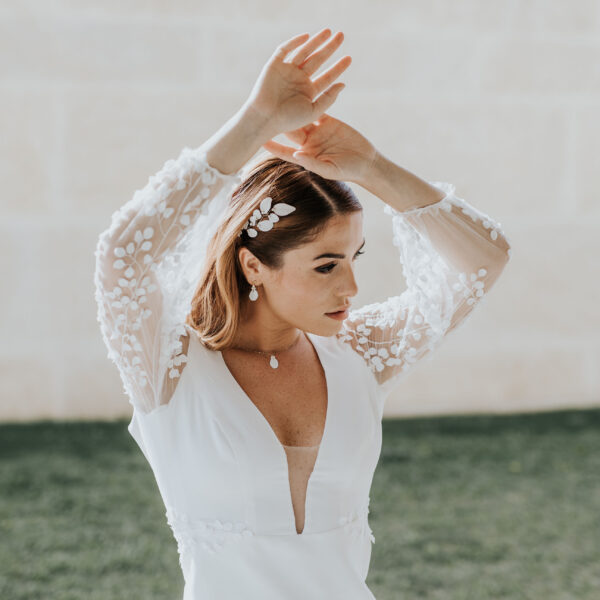 bijoux de mariage en porcelaine portés par une mariée. Elle porte une vigne de cheveux, des fines boucles d'oreilles et un collier pendant.