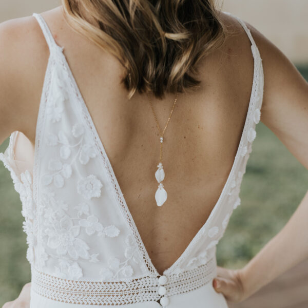 Collier de dos avec deux pétales en porcelaine porté par une mariée ayant une robe dos nu.