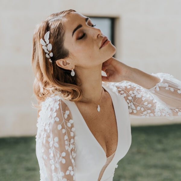 bijoux de mariage en porcelaine portés par une mariée. Elle porte une vigne de cheveux, des fines boucles d'oreilles et un collier pendant.