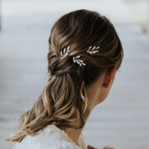 Accessoires cheveux de mariage en nacre et perles de Swarovski, portés par un mariée. Ces bijoux de mariage sont composés d'épingles à chignon.