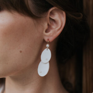 Mariée portant boucles d'oreilles de mariage longues en porcelaine minimalistes et élégantes.