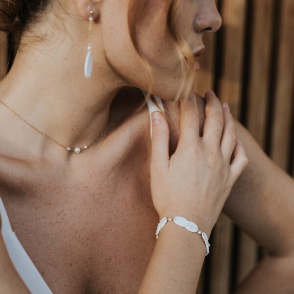 Mariée portant ses bijoux de mariage en porcelaine et perles.