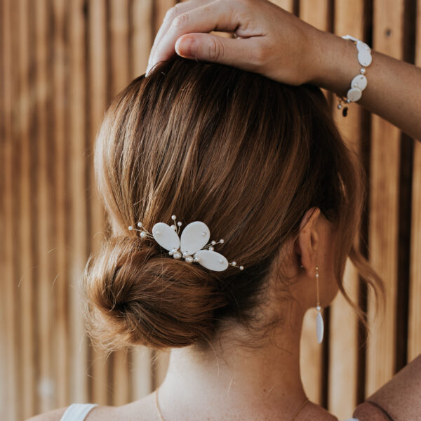 Mariée portant dans son chignon un peigne de mariage en porcelaine et perles de Swarovski, au poignet elle porte un bracelet et des boucles d'oreilles pendantes.