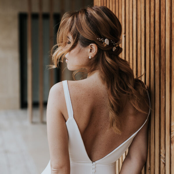 Mariée aux cheveux lachés portant des bijoux de cheveux en porcelaine, perles et feuilles dorées.