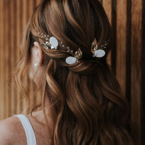 Mariée aux cheveux lachés portant des bijoux de cheveux en porcelaine, perles et feuilles dorées.