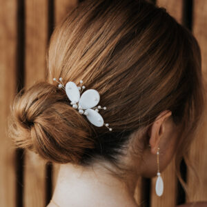 Mariée portant dans son chignon un peigne de mariage en porcelaine et perles de Swarovski et des boucles d'oreilles pendantes.