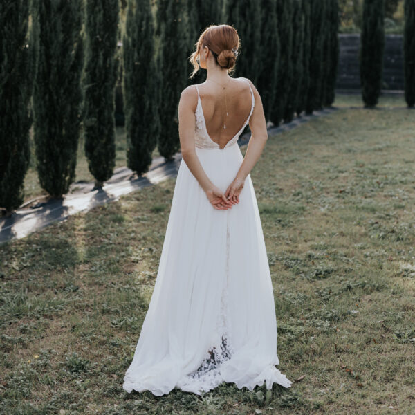 Dans un paysage provençale, une mariée porte ses bijoux de mariage. Sur sa robe dos nu, elle porte un pendentif de dos et dans son chignon de mariée des épingles à cheveux.