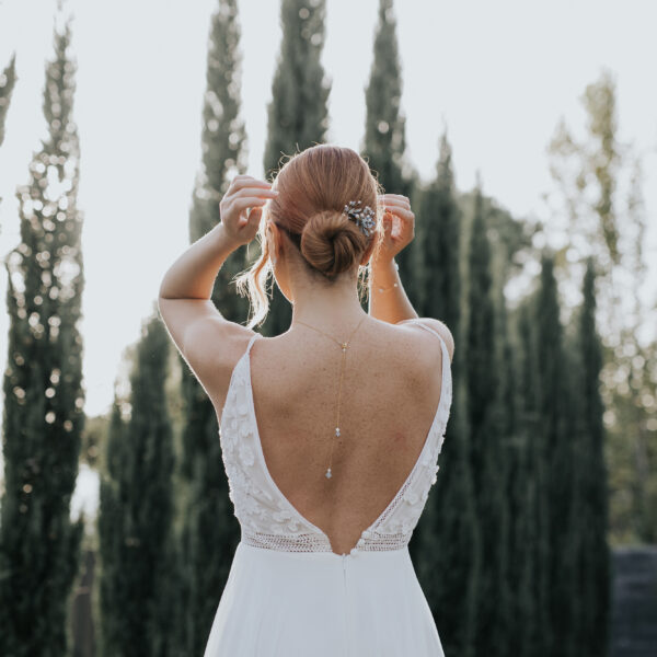 Bijoux de mariage en perles d'eau douce et perles bleu opal, portés par un mariée vue de dos. Sur sa robe dos nu elle porte un pendentif de dos et dans un chignon bas elle porte un élégant set d'épingles à cheveux.