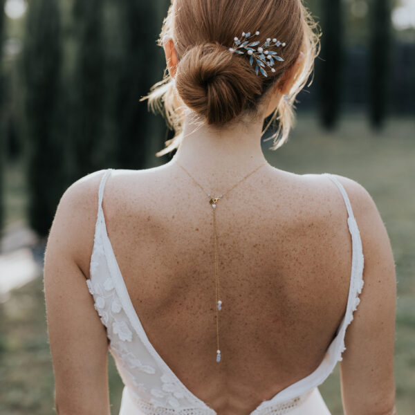 Bijoux de mariage fins et élégant et perles d'eau douce et perles bleu opal, portés par une mariée. Elle porte un pendentif de dos sur sa robe dos nu et un ravissant set d'épingles à chignon dans sa coiffure de mariée.