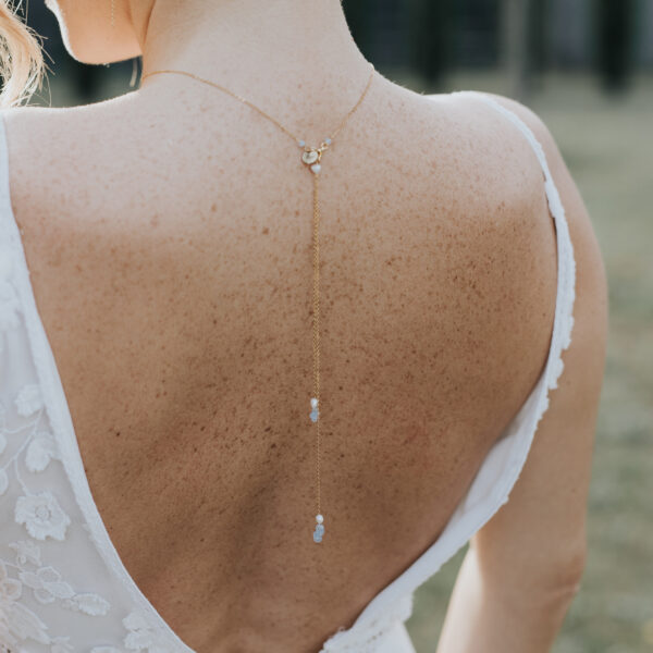 Jeune mariée vue de dos, portant un pendentif de dos en perles d'eau douce et perles bleu opal.