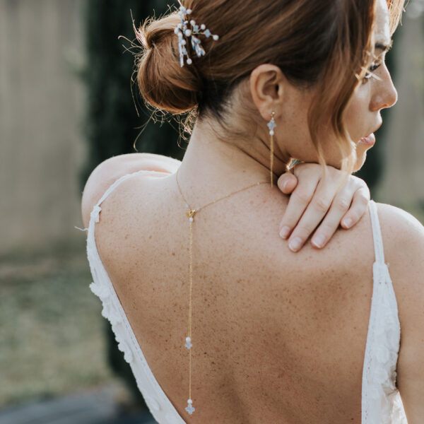 Bijoux de mariage en perles d'eau douce et perles bleu opal, portés par une mariée vue de dos. Elle porte un pendentif de dos, des boucles d'oreilles pendantes et des bijoux dans sa coiffure de mariage.