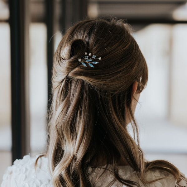 Coiffure de mariage semi-attachée habillée d'une épingle à chignon en perle d'eau douce et perle bleu opal.