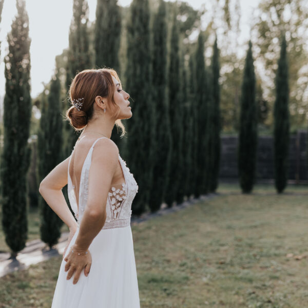 Une mariée vue de profil porte des bijoux de mariage. Des boucles d'oreilles fines et pendantes et et épingles à chignon en perles d'eau douce et perle bleu opal.